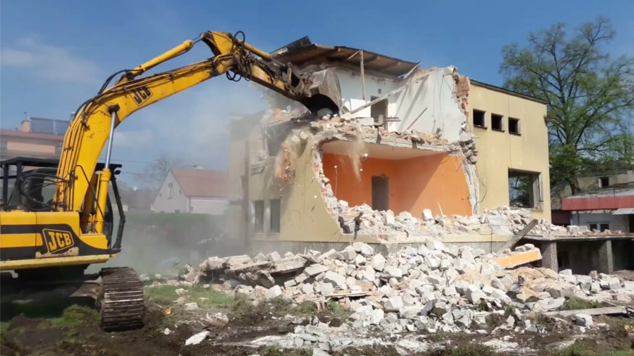 Koparka JCB podczas rozbiórki murowanego budynku