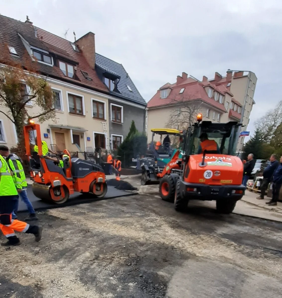 Układanie nawierzchni drogowej, walec i ładowarka podczas robót drogowych