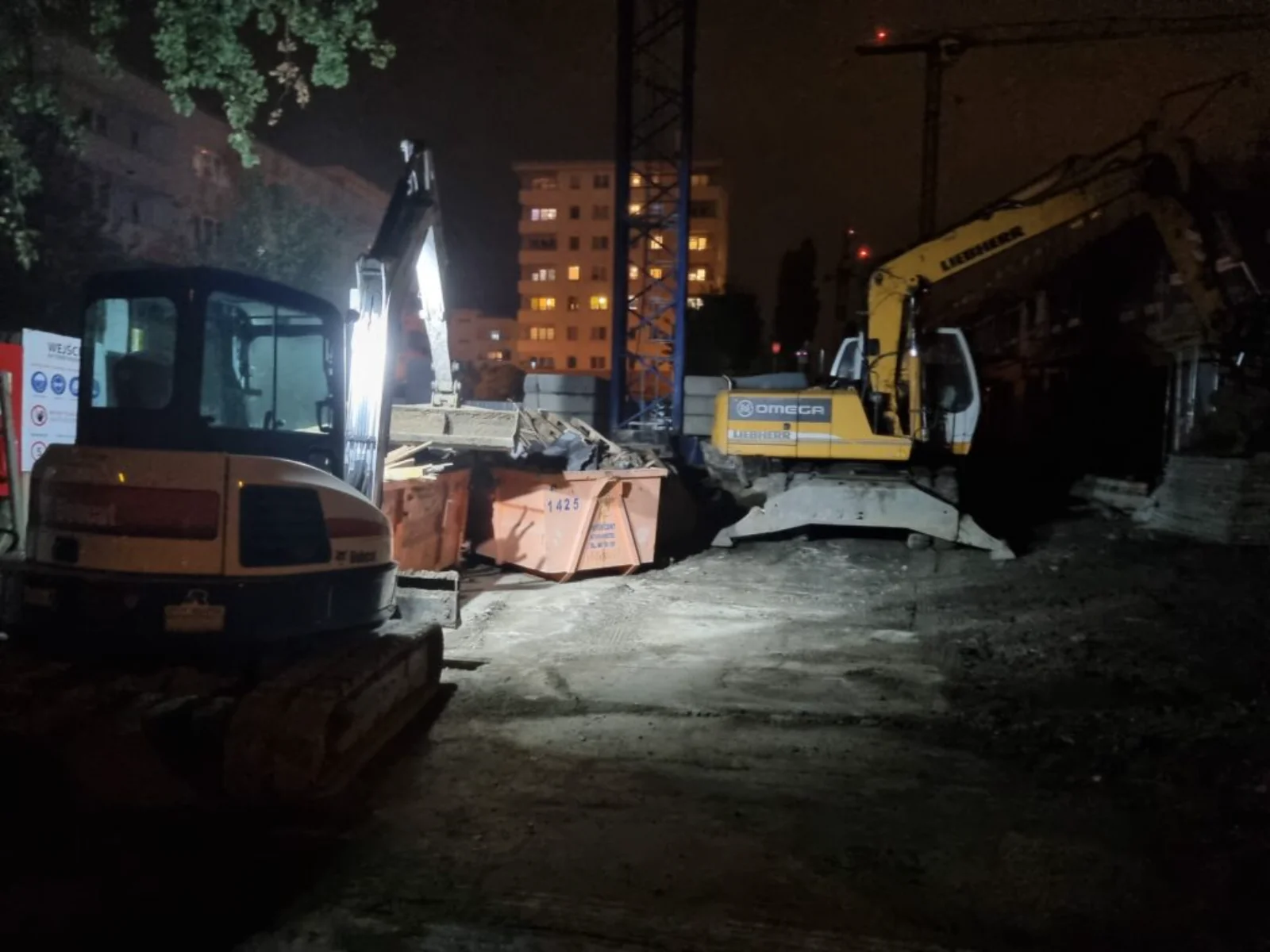 Nocna rozbiórka w mieście, koparka Liebherr Omega i kontener na gruz